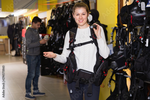 Female is standing with modern diving vest in the store. © JackF