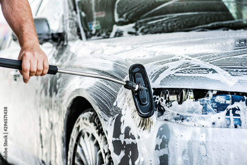 Man cleaning a car with brush and water. Detal of washing a vehicle