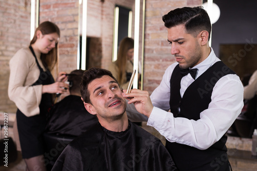 Male getting shave with straight razor in salon photo