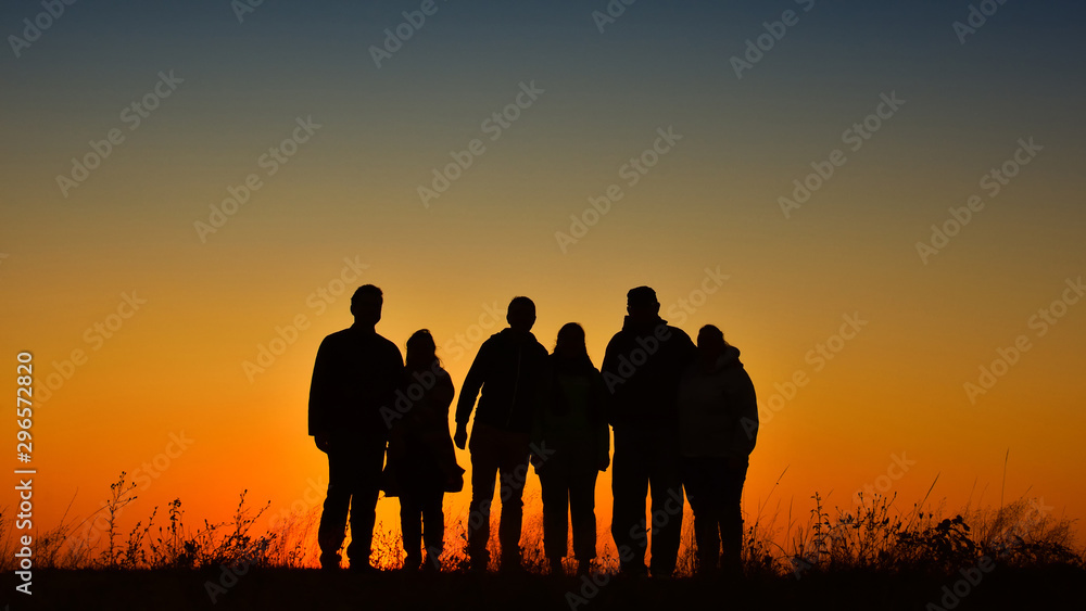 Three families silhouette gathering for a photo at sunset
