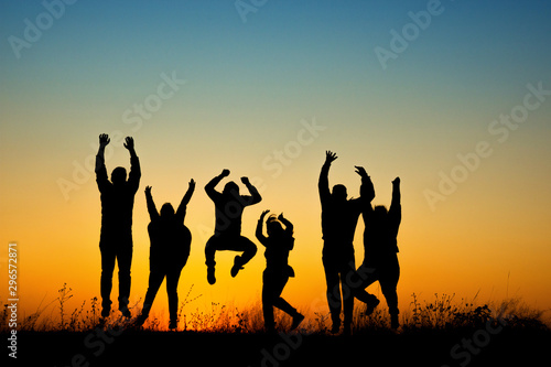Happy people silhouette jumping in sunset