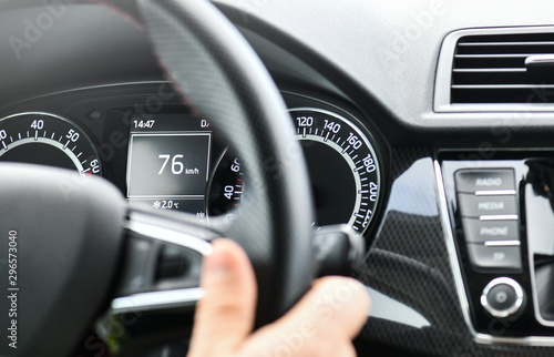 The driver is holding the steering wheel with right hand. View on dashboard detail on speed meter.
