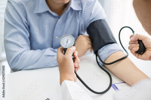 Doctor man is checking the blood pressure of the patient. photo