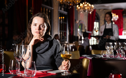 Young woman holding glass of white wine in luxurious restaurant