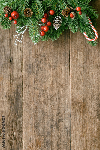 Wood table plank in vertical with pine leaves and pine cones, holly balls and candy cane in Christmas theme concept. Wooden background in top view flat lay with copy space for Christmas wallpaper.