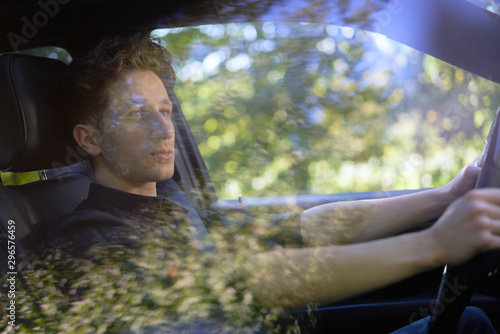 Handsome young driver in a car with beautiful reflections 