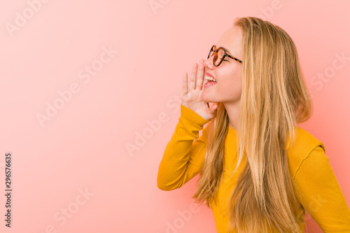 Adorable teenager woman shouting and holding palm near opened mouth.