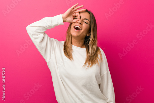 Young authentic charismatic real people woman against a wall excited keeping ok gesture on eye.