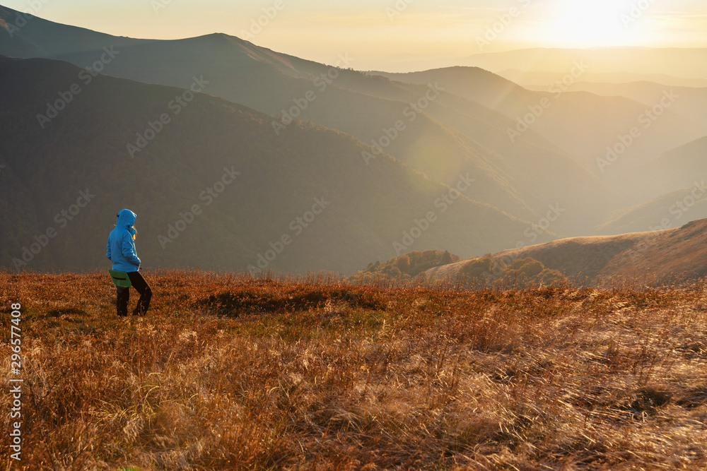 Young girl travels through beautiful mountain ranges with fantastic views of autumn meadows and peaks