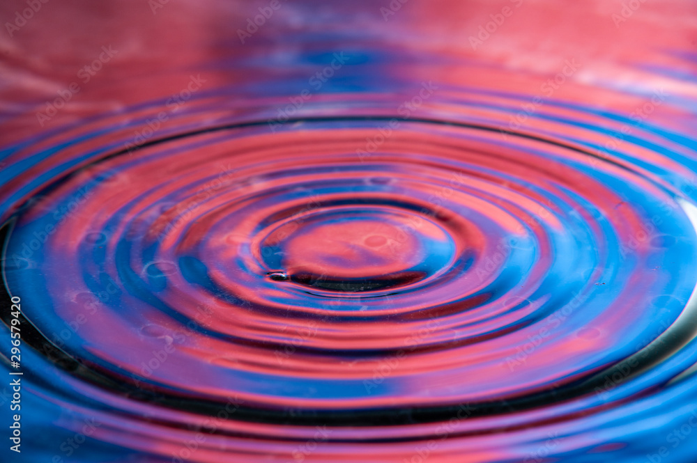 Vibrant red and blue circular ripples. High speed water drop photography