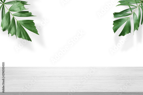 white wooden table top with green palm leave for product advertisement display