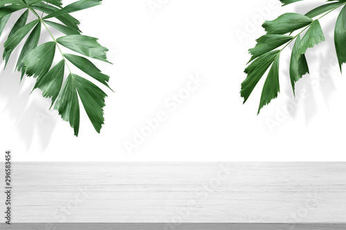white wooden table top with green palm leave for product advertisement display