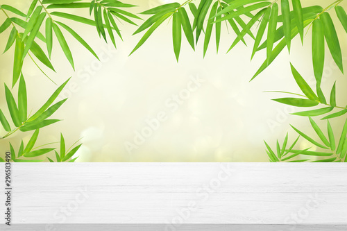 white wooden table top with beautiful green bamboo leave background for advertisement display