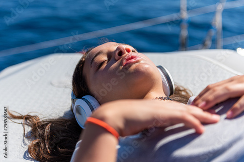 cute young girl is listening to her favorite music while laying on a yacht photo