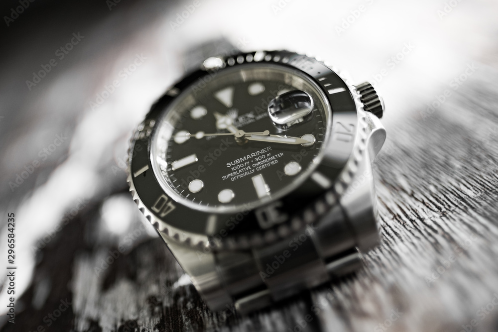 Close-up, abstract and shallow focus view of an iconic, swiss-made men's automatic divers watch showing the ceramic bezel and famous cyclops date lens. Close-up, abstract and shallow focus view of an iconic, swiss-made men's automatic divers watch showing the ceramic bezel and famous cyclops date lens.