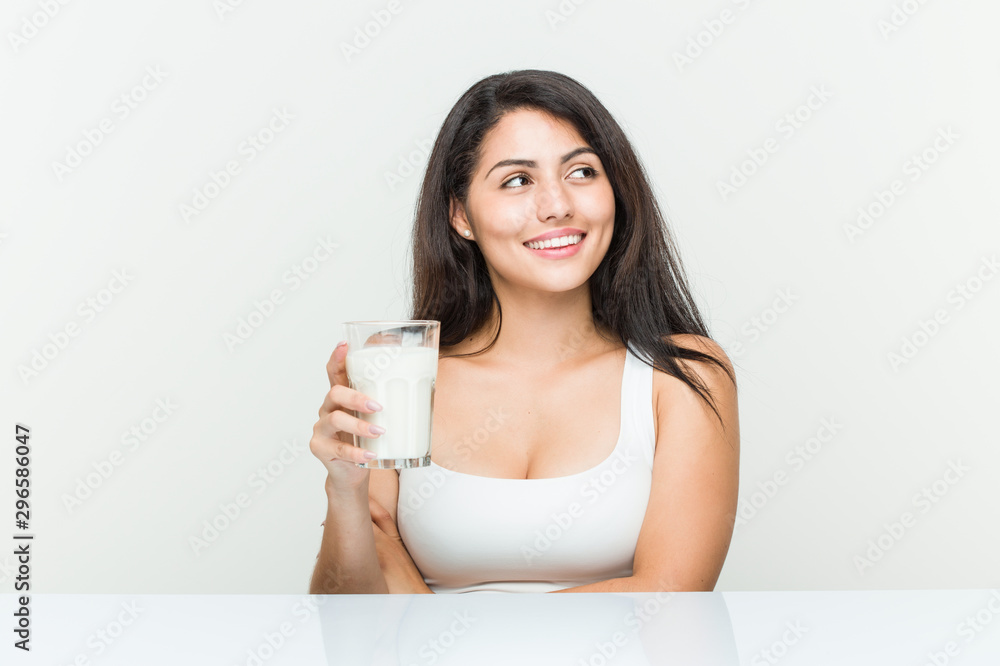 Young hispanic woman holding a glass of milk smiling confident with crossed arms. Young hispanic woman holding a glass of milk smiling confident with crossed arms.