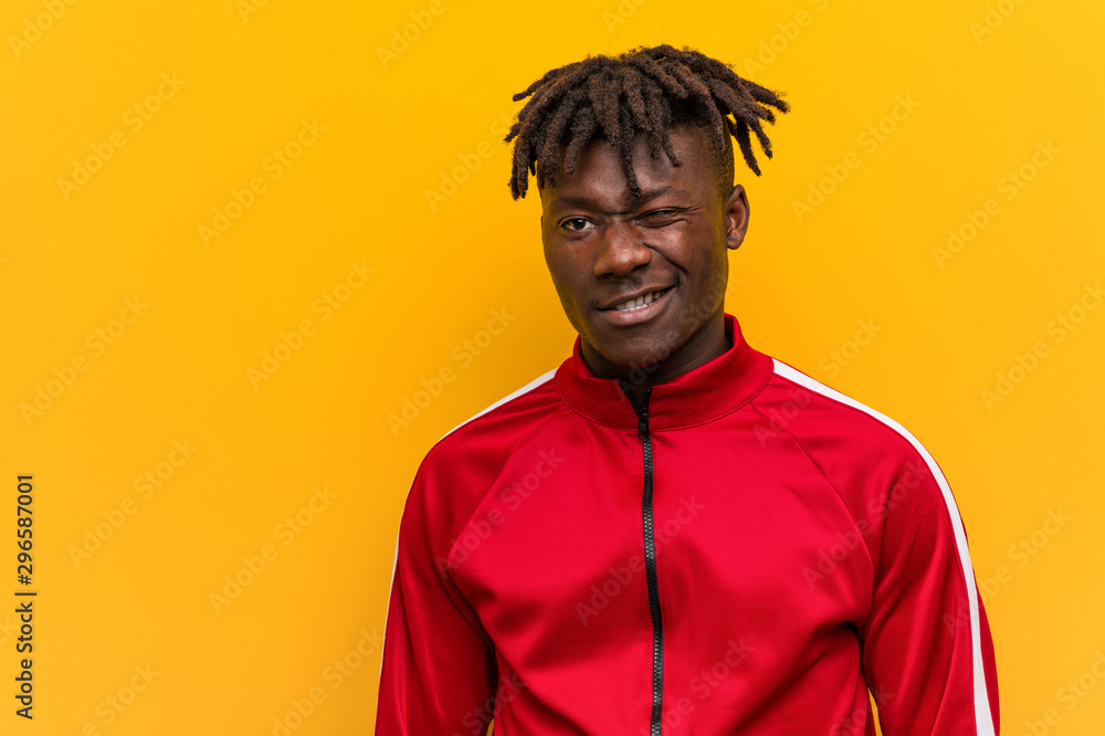 Fototapeta premium Young fitness black man winking, funny, friendly and carefree.