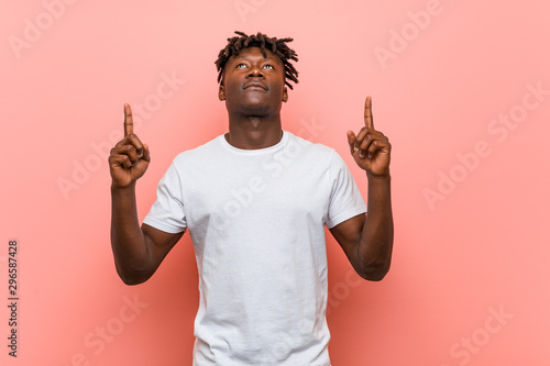 Young african black man pointing upside with opened mouth.