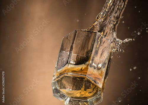 falling glass with whiskey and spray on a brown background