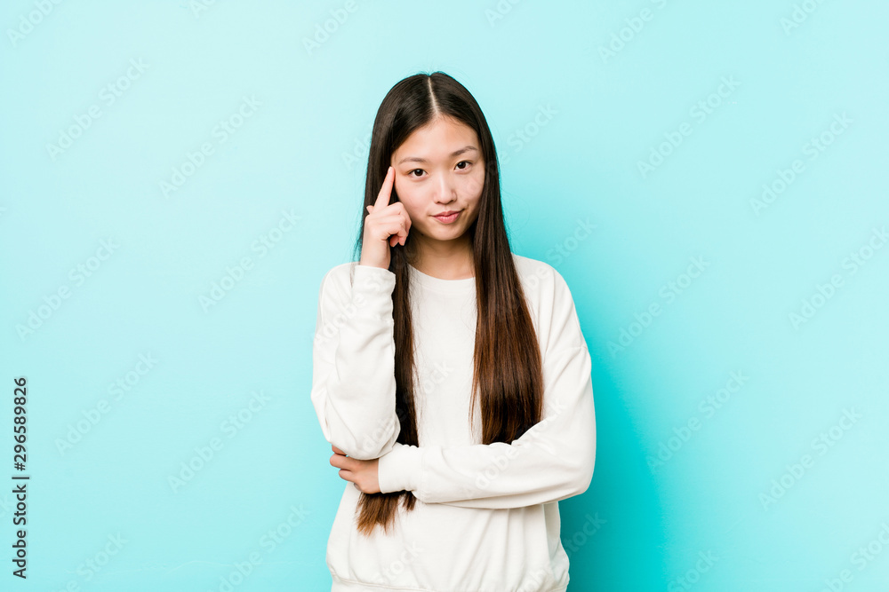 Young pretty chinese woman pointing temple with finger, thinking, focused on a task. Young pretty chinese woman pointing temple with finger, thinking, focused on a task.