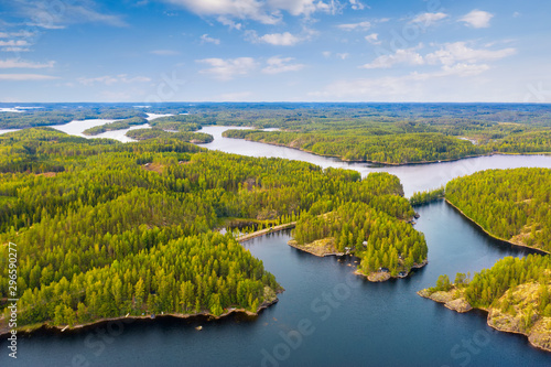 Fototapeta Naklejka Na Ścianę i Meble -  Aerial view of road between green summer forest and blue lake in Finland