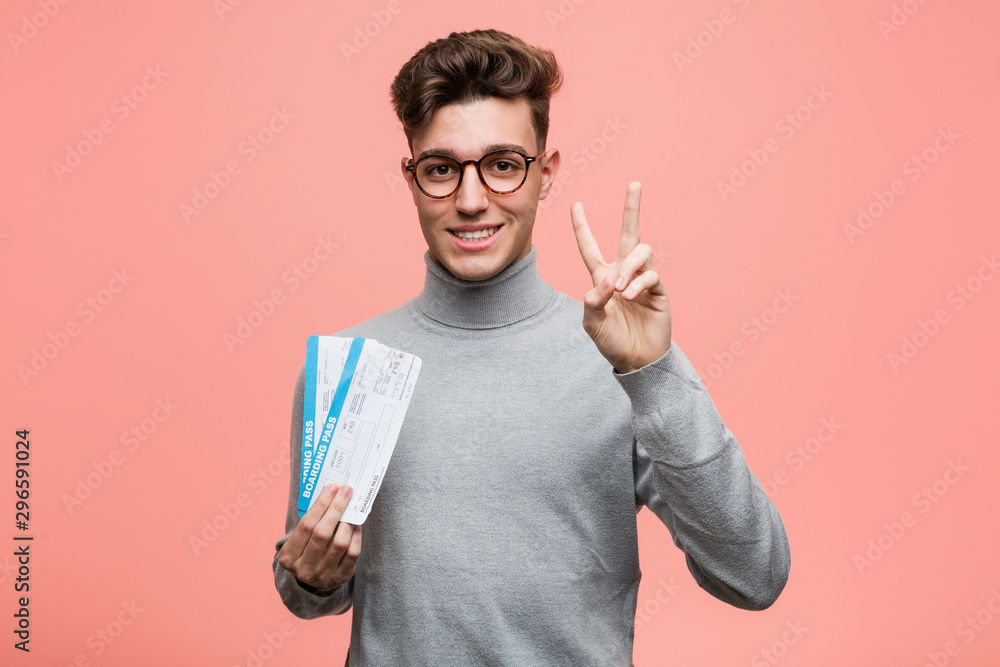 Young cool man holding an air tickets showing number two with fingers. Young cool man holding an air tickets showing number two with fingers.