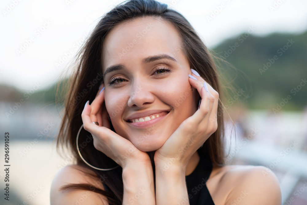 Fototapeta premium Young pretty likable cheerful woman posing summer city outdoor in Kyiv, Ukraine. Beautiful self-confident girl with long brown hair posing on Dnipro river bank enjoing her life, urban lifestyle