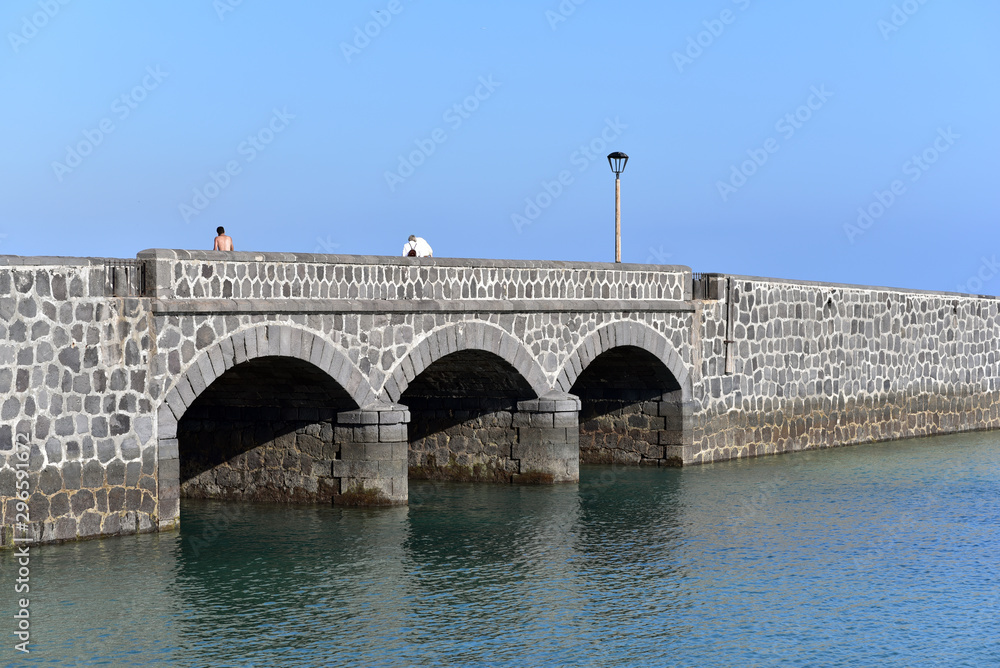 Fototapeta premium People on the Puente de las Bolas, drawbridge in front of the fort of Castillo de San Gabriel, Arrecife, Lanzarote, Canary Islands, Spain 