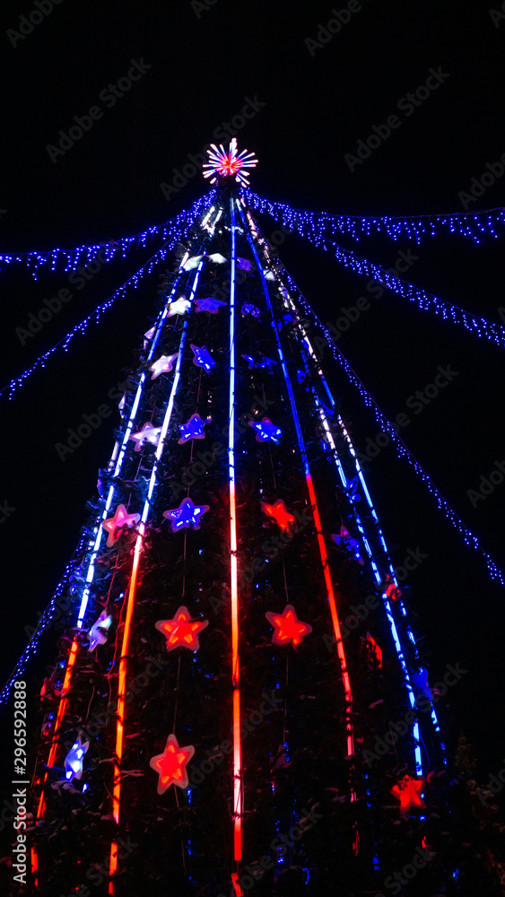 Obraz premium Christmas tree with lights on black background at night vertical photo
