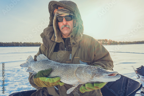 Winter fishing catch trophy outdoor activities hobby. A man holds a large fish pike