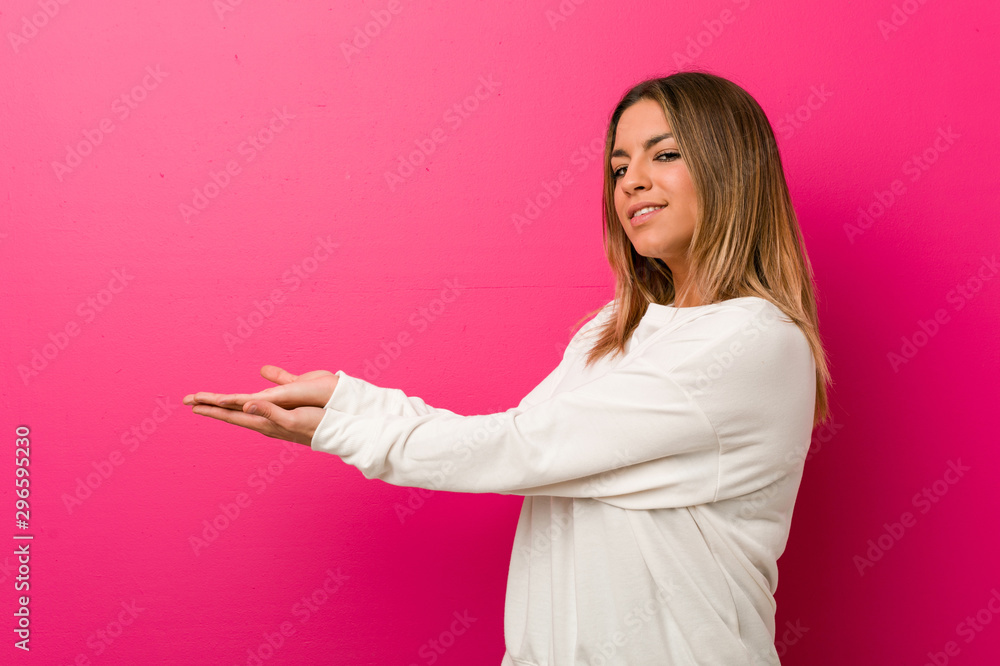 Young authentic charismatic real people woman against a wall holding a copy space on a palm. Young authentic charismatic real people woman against a wall holding a copy space on a palm.