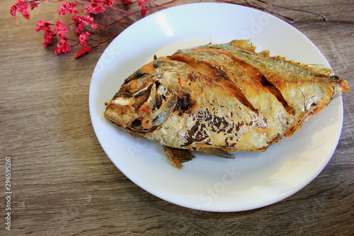 Fried fish in a white plate on the gray table.
