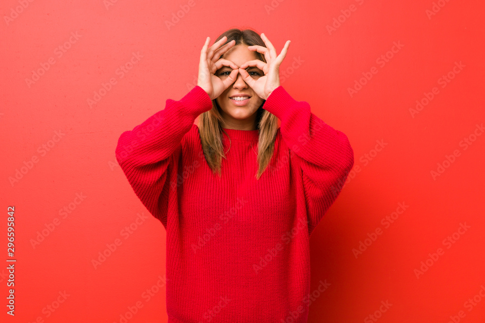 Fototapeta premium Young authentic charismatic real people woman against a wall showing okay sign over eyes
