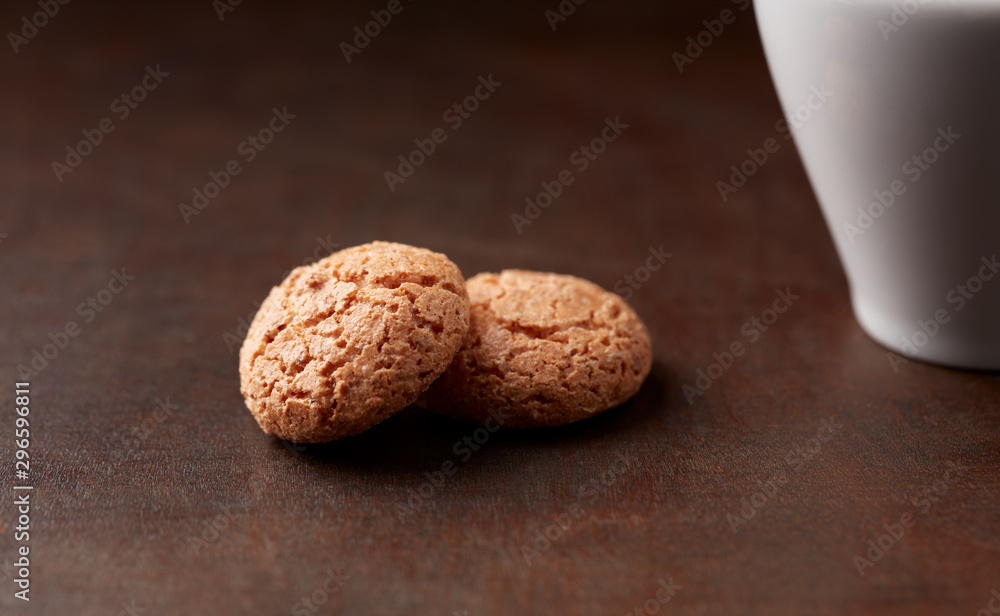 Amaretti (Italian biscuits) and a cup of coffee on dark wooden background. Close up. 