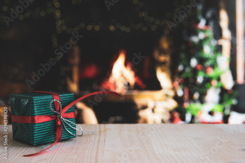 Wooden table with blurred christmas background and gift.