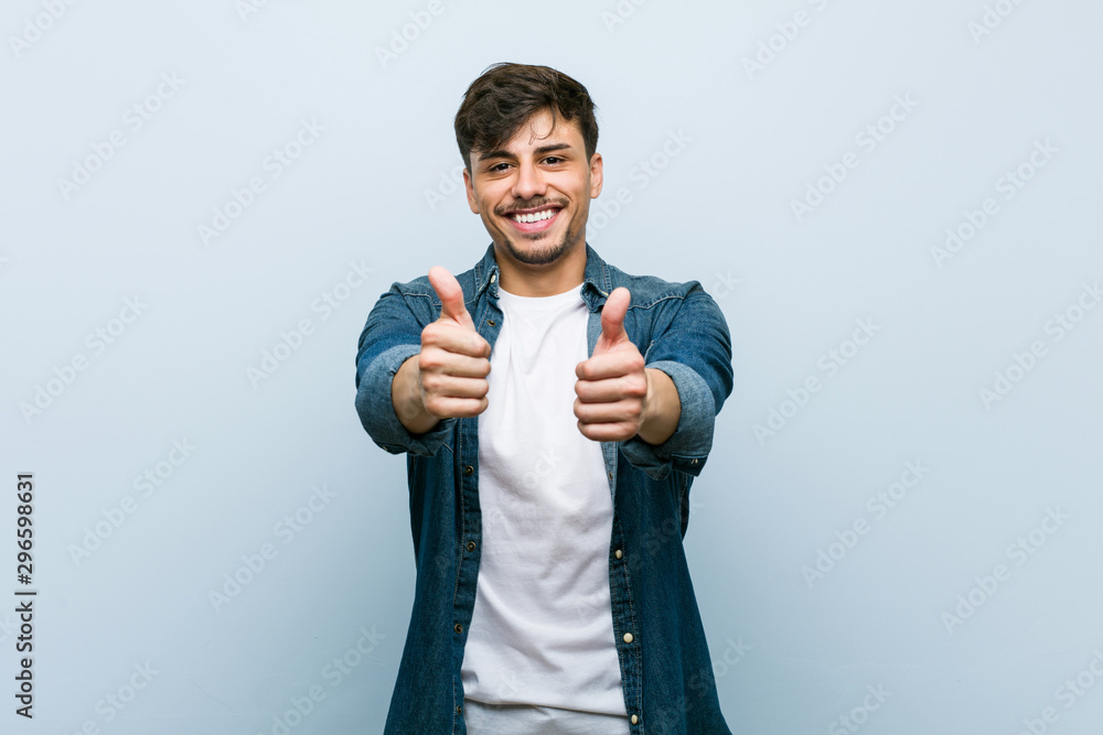 Young hispanic cool man with thumbs ups, cheers about something, support and respect concept. Young hispanic cool man with thumbs ups, cheers about something, support and respect concept.