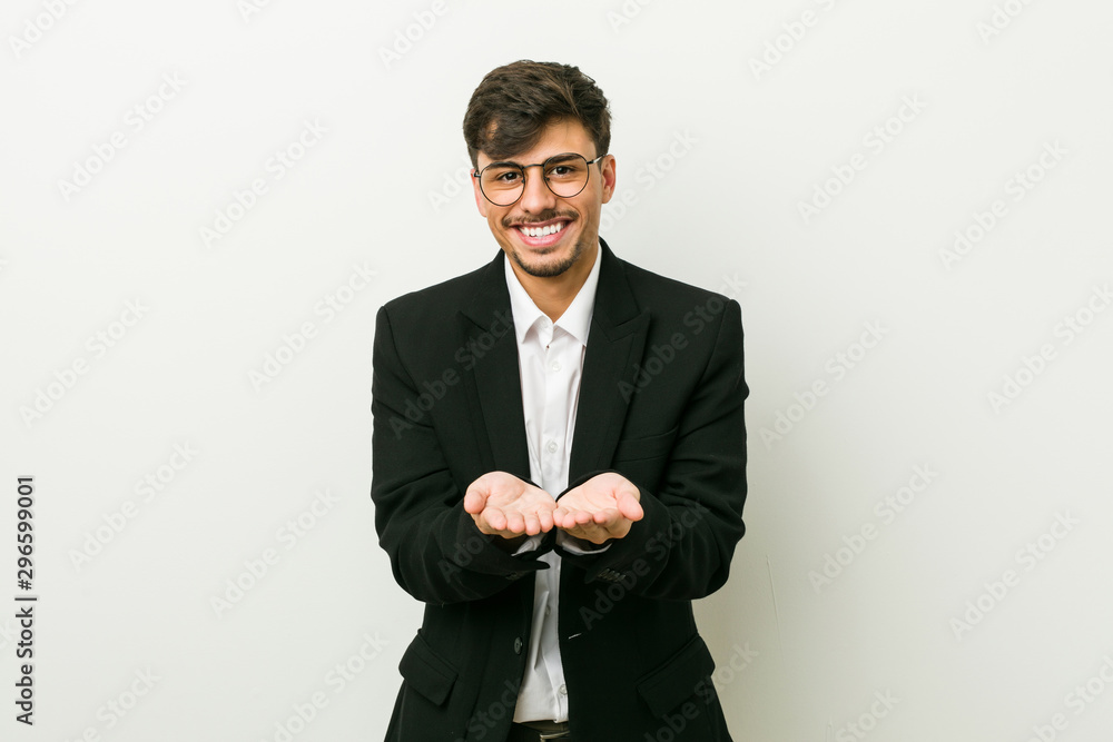 Young business hispanic man holding something with palms, offering to camera. Young business hispanic man holding something with palms, offering to camera.