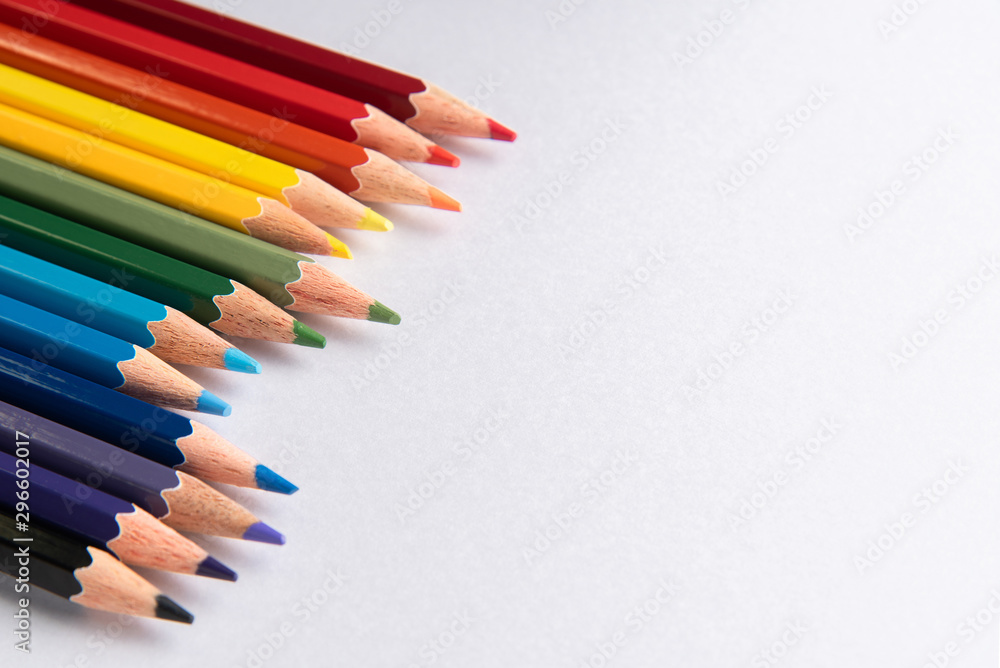 Colored pencils arranged in diagonal line on white paper background Colored pencils arranged in diagonal line on white paper background