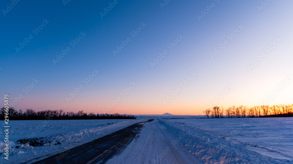Sunset on the snow country road in winter time