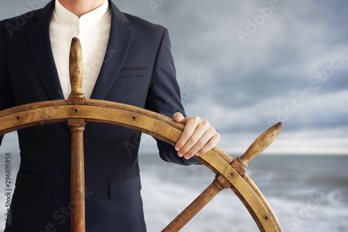 Businessman holding ship wheel and navigates in storm. photo