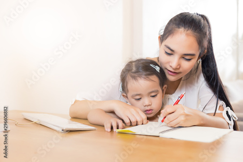 Young Asian beautiful mom with her daugther kid work at home.