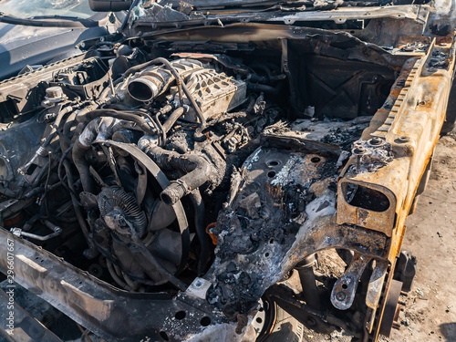 A burnt car engine with propeller after a fire or an accident in a parking lot covered with rust and black coal with scattered spare parts around. Robbery, arson, terrorism.