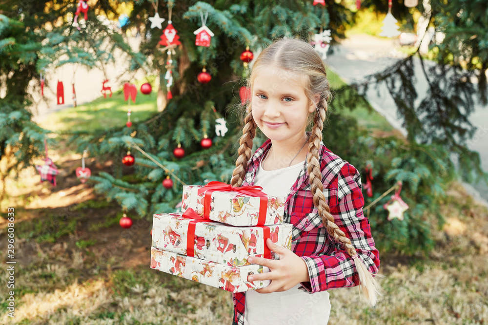 Family Christmas in July. Portrait of girl near christmas tree with gifts. Baby decorating pine. Winter holidays and people concept. Merry Christmas and Happy Holidays Greeting card. Christmas child