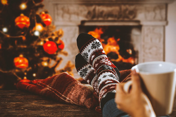 Woman legs with christmas socks and fireplace 