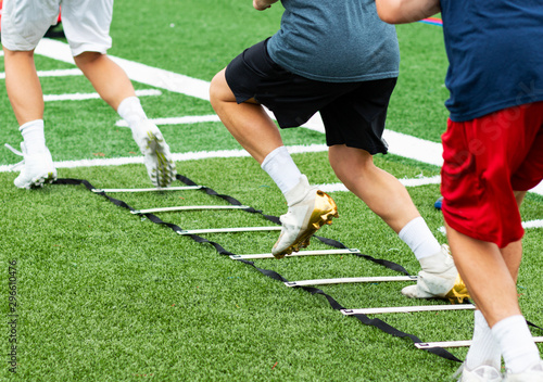 Konstfotografi Three athletes in cleats doing ladder foot drills on turf field