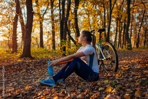 Riding bicycle in autumn forest. Young woman having rest after workout on bike. Healthy lifestyle
