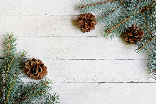 Christmas tree branch with pine cones on white wooden background with copy space photo