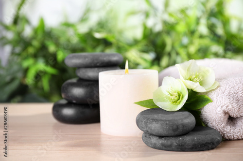 Composition with spa stones, towel and candle on wooden table, space for text