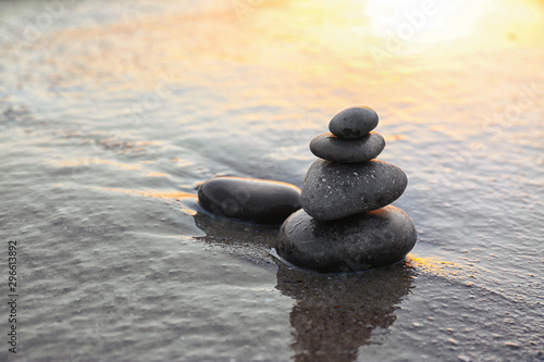 Dark stones on sand near sea at sunset  space for text. Zen concept