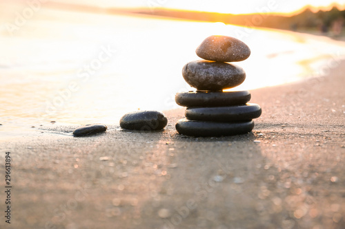Dark stones on sand near sea at sunset  space for text. Zen concept